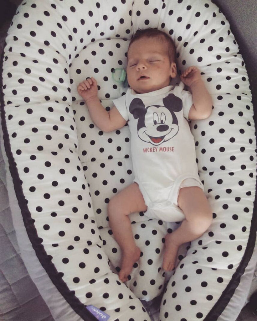 Baby sleeping in a polka dot designed portable crib