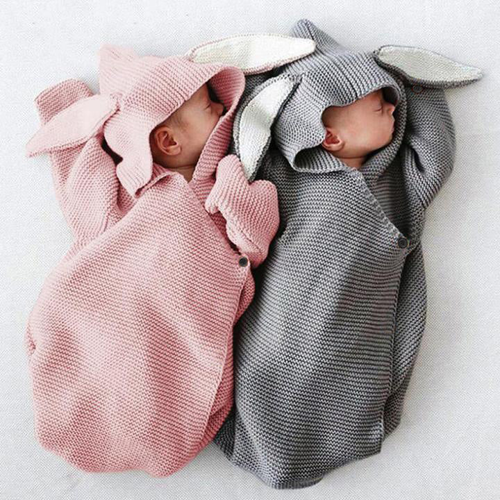 Two babies in a pink and grey bunny style baby sleeping bag